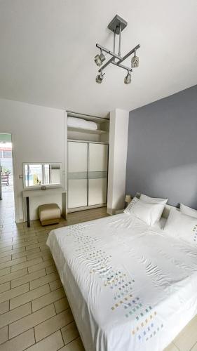 a bedroom with a large white bed and a chandelier at Seaside Apartments - Adults Only in Yenion