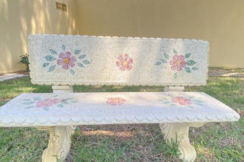 a bench with flowers on it sitting in the grass at Jacaranda in Cádiz