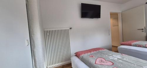 a room with two beds and a tv on the wall at Renatas Ferienwohnung Maria in Sasbachwalden