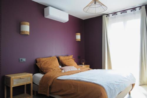 une chambre avec un lit avec un mur violet dans l'établissement Maison spacieuse et accès indépendant au centre-ville de Tournus, à Tournus
