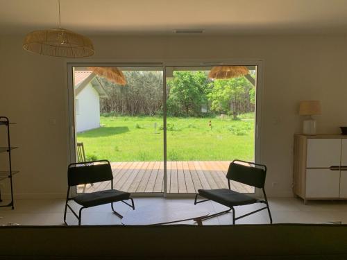 - un salon avec deux chaises et une porte coulissante en verre dans l'établissement Les Nids de Galleben - La Villa Biscarrosse, à Liposthey