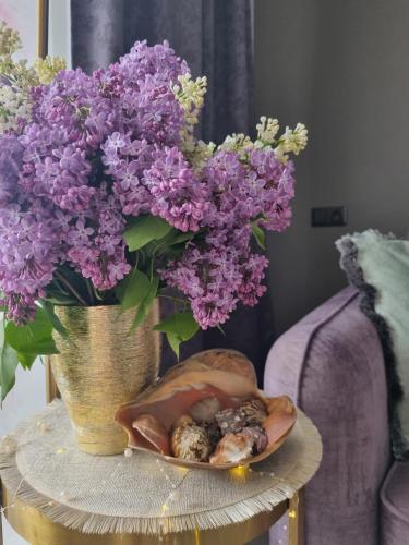a vase filled with purple flowers and a plate of food at Few Steps to the Bay in Jūrmala