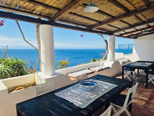 a patio with a table and a view of the ocean at Villa Vista Mare a Filicudi in Filicudi