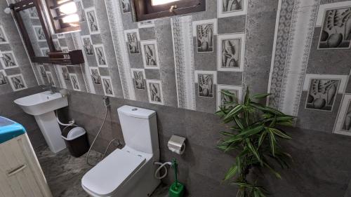 a bathroom with a toilet and a sink and pictures on the wall at Galhena Villa in Tangalle