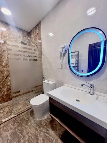 a bathroom with a white toilet and a mirror at Baza Hotel Spa in Beylǝqan