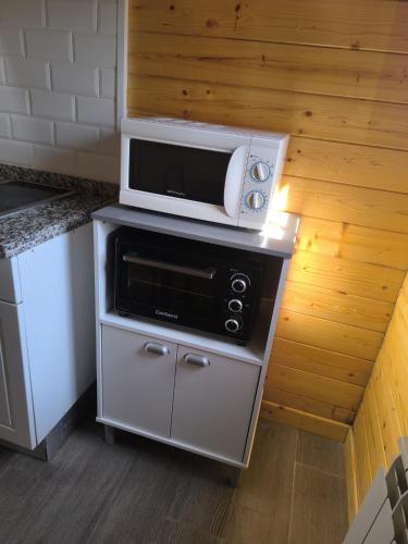 a microwave on top of a stove in a kitchen at Cabañas Miraduero in Aldeadávila de la Ribera
