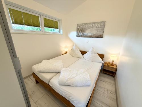 a small bedroom with a bed with white sheets and pillows at Die 5 Ferienwohnungen der Familie Weber in Fehmarn