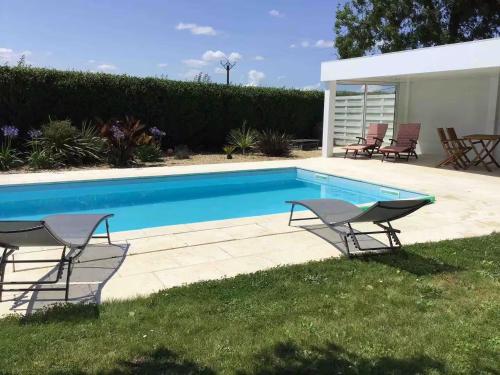 - une piscine avec 2 chaises dans l'herbe dans l'établissement Maison de caractère à Corseul, jardin et piscine, à Corseul