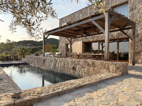 una casa con una pared de piedra junto a una piscina en Villa Sabbia, en Lecci