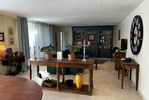 - un salon avec une table et une horloge murale dans l'établissement Le Mas Magnan, à Saint-Alexandre