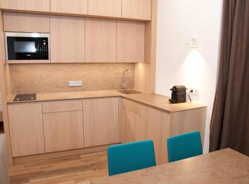 a kitchen with a sink and a counter with blue chairs at Seeappartements Bürger in Krumpendorf am Wörthersee