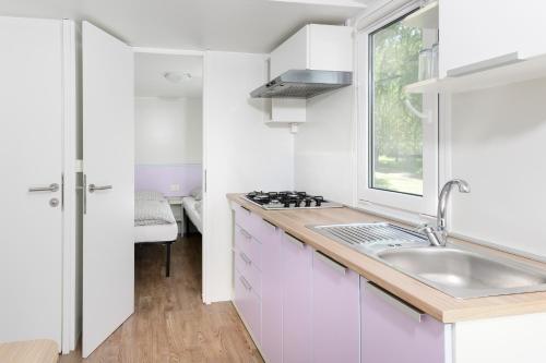a white kitchen with a sink and a window at Camping 2000 in Januv Dul