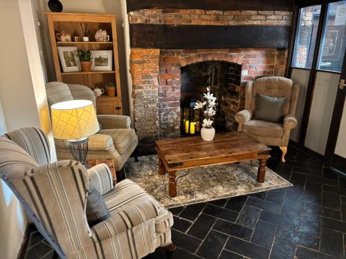 a living room with chairs and a brick fireplace at Thatched Cottage Hotel in Brockenhurst