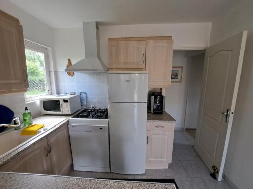 eine Küche mit einem weißen Kühlschrank und einer Mikrowelle in der Unterkunft Pause zen dans le Perche Nature & calme 