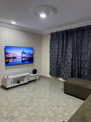 a living room with a flat screen tv and a couch at Adwoa Gyemfua's Haven in Trofwi