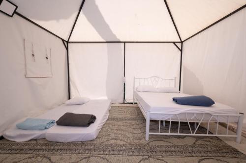 基内雷特גלמפינג האון בכנרת的一间白墙房间里有两张床