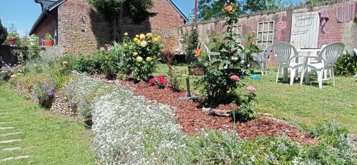 a garden with flowers and a table and chairs at Chez Alex' guesthouse in Dozulé