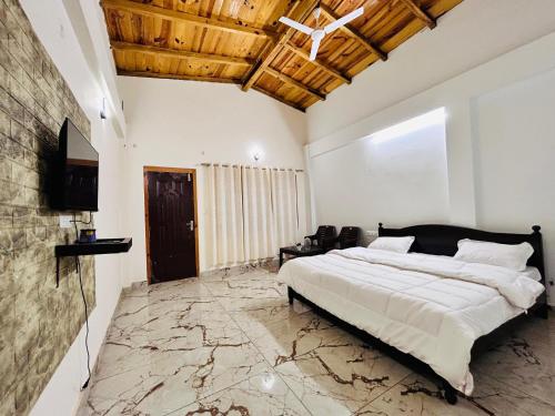 a bedroom with a large bed and a television in it at Lotus Lake View Inn in Bhīm Tāl