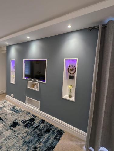 a wall with a flat screen tv and paintings on it at LuxeView - Stylish & Comfortable 1 Bedroom House in Chafford Hundred in North Stifford