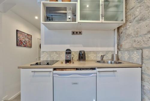 une petite cuisine avec des armoires blanches et un évier dans l'établissement Studio walking distance from Marais with mobile AC, à Paris