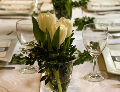 a vase of flowers on a table with wine glasses at Gasthaus Korfu in Edenkoben