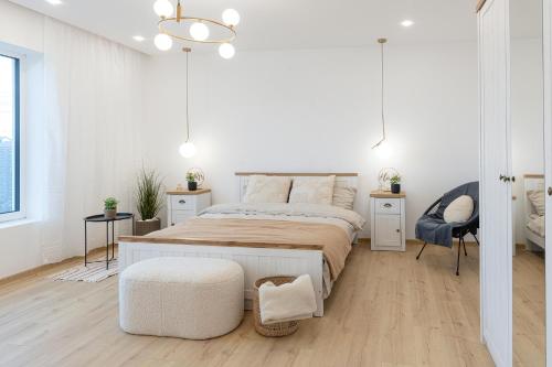 a white bedroom with a large bed and a chair at Amavi Homes With Garden in Alba Iulia