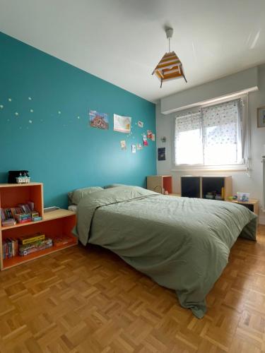 une chambre avec un lit et un mur bleu dans l'établissement Appartement familiale Paris - Mairie des Lilas, aux Lilas