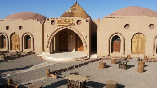 a large building with a tower and a courtyard at Qasr El Bagawat Hotel in ‘Ezbet Halfa