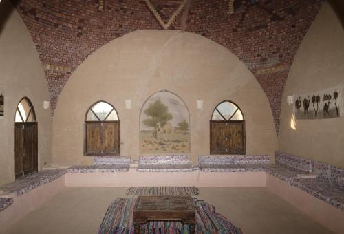 an empty room with two arched windows and a table at Qasr El Bagawat Hotel in ‘Ezbet Halfa