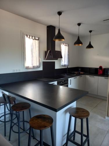 une cuisine avec un comptoir noir et deux tabourets dans l'établissement Casa di l Alivetu, à Ventiseri