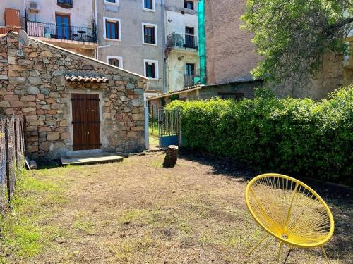 une raquette de tennis jaune posée dans une cour à côté d'un bâtiment dans l'établissement Bergerie corse avec vue mer, à Piana
