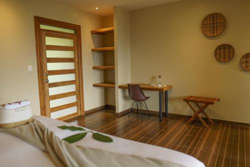 a room with a bed and a table and a chair at Vibra Healing Lodge y Spa in Teniente Hugo Ortiz