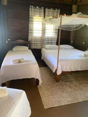 a bedroom with two beds with white sheets at Estrela dos Lençóis in Atins