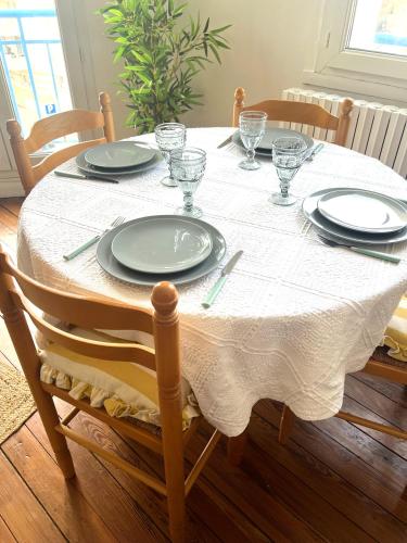 une table de salle à manger avec des assiettes et des verres dessus dans l'établissement Le cosy Terminus - Le havre - 2 chambres -1 min à pied de la gare, au Havre