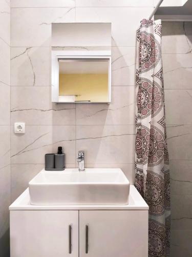 a bathroom with a white sink and a shower curtain at Sokrates Apartments in Preveza