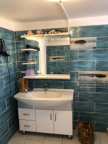 a bathroom with a sink and a mirror and blue tiles at la maison des bois flottés in Port-Louis