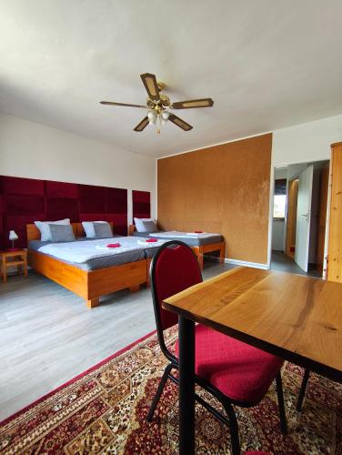 a bedroom with a bed with a ceiling fan and a table at Penzion U Ježů - Ubytování in Pasohlávky