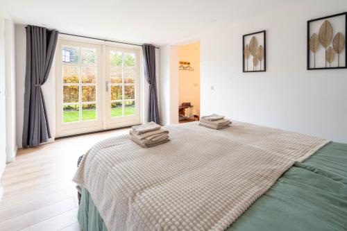 WeiteveenにあるLuxe Hottub Huisje Bij het Veen op de rand van het Bargerveen Drentheのベッドとタオル2枚のある寝室