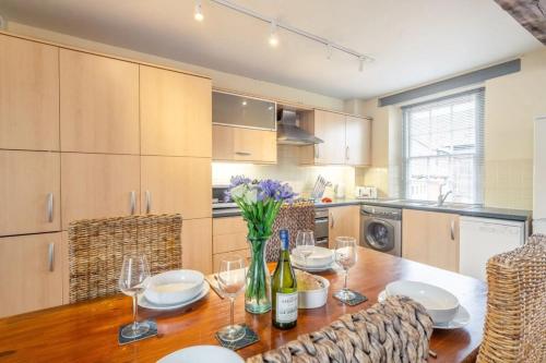 a kitchen with a wooden table with wine glasses at Picture Perfect Location Stunning 2 Bedroom Apartment with parking in Norwich