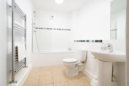 a white bathroom with a toilet and a sink at Picture Perfect Location Stunning 2 Bedroom Apartment with parking in Norwich