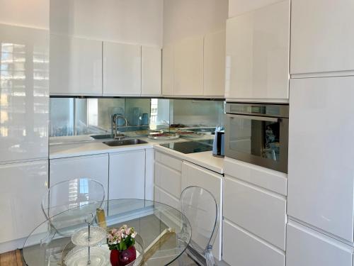 a kitchen with white cabinets and a glass table at Luxury Tenao palace, Monaco border, sea view in Beausoleil