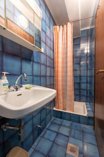a blue tiled bathroom with a sink and a shower at Apartments Petrali in Mlini