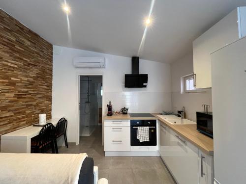 - une cuisine avec des placards blancs et un lit dans une chambre dans l'établissement Petit appartement de 35 m2 au Puig del Mas, à Banyuls-sur-Mer