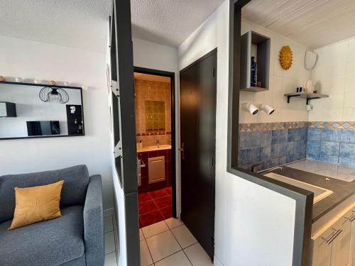 Ce petit appartement dispose d'un canapé bleu et d'une cuisine. dans l'établissement L'Azur, T2 - Parking gratuit - Central - confort Cosy, à Sète