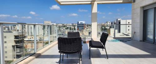 a balcony with chairs and a view of a city at The spectacular tallest penthouse in the city 4-BR in Qiryat Ata