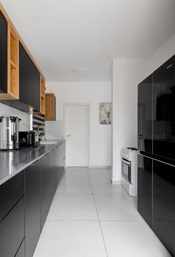 a white kitchen with black cabinets and a white floor at The spectacular tallest penthouse in the city 4-BR in Qiryat Ata