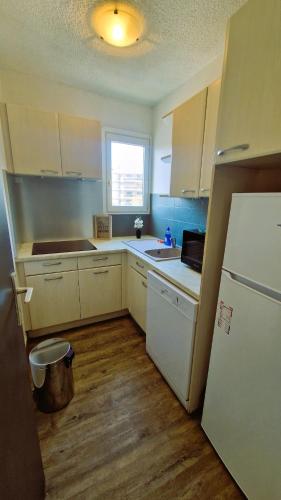 une cuisine avec des armoires blanches et un réfrigérateur blanc dans l'établissement Appartement Vasco - Esterel Experience, à Saint-Raphaël