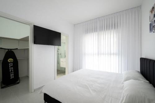 a white bedroom with a bed and a window at Wonderful 4-BR APT in the center in Qiryat Ata