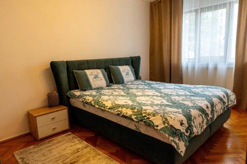 a bedroom with a bed with a green headboard and a window at RUM Apartment in Cluj-Napoca