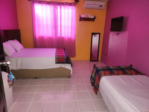 two beds in a room with pink and purple walls at EL REY Hotel & Restaurant in Belmopan